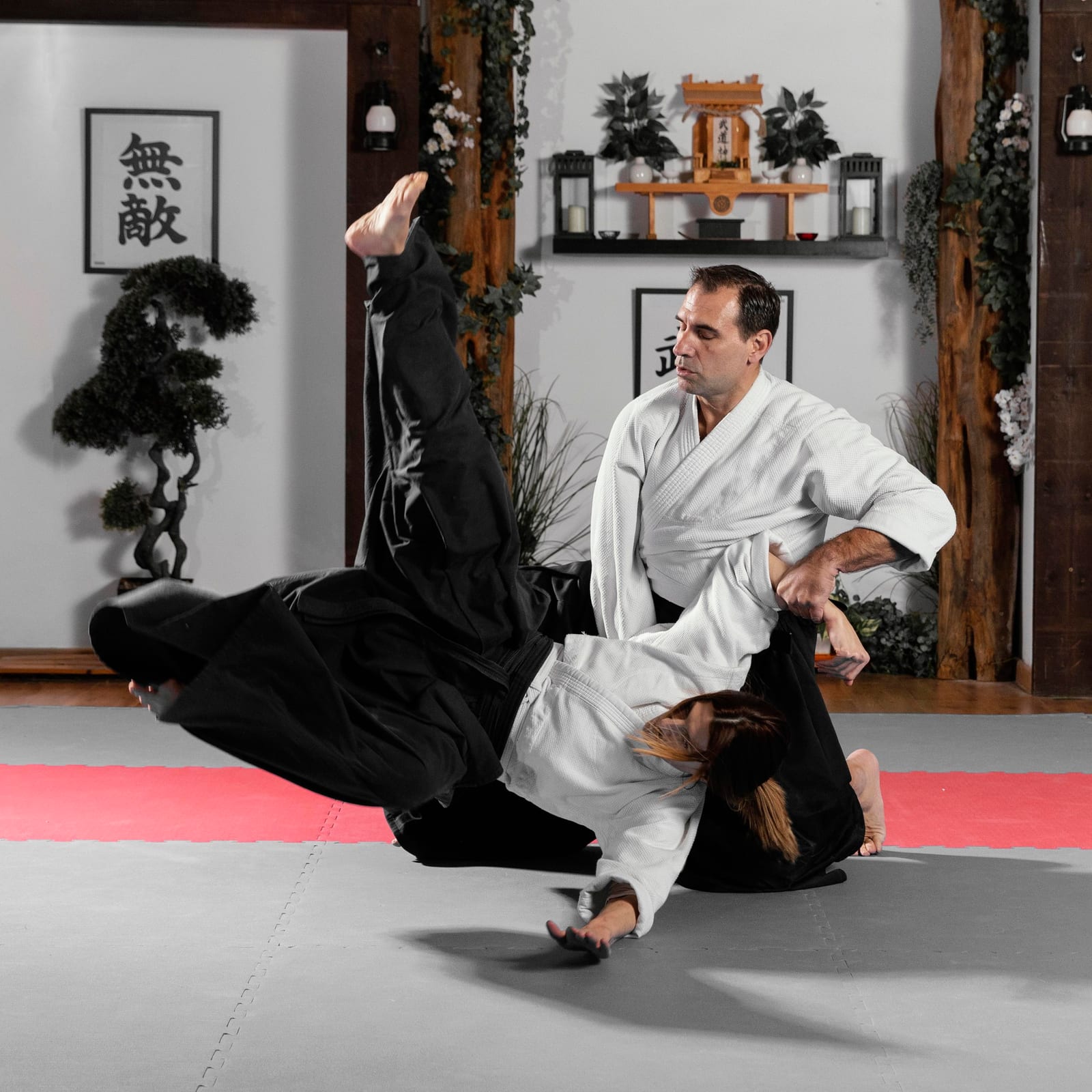 An instructor guiding a student through a controlled takedown on a training mat.